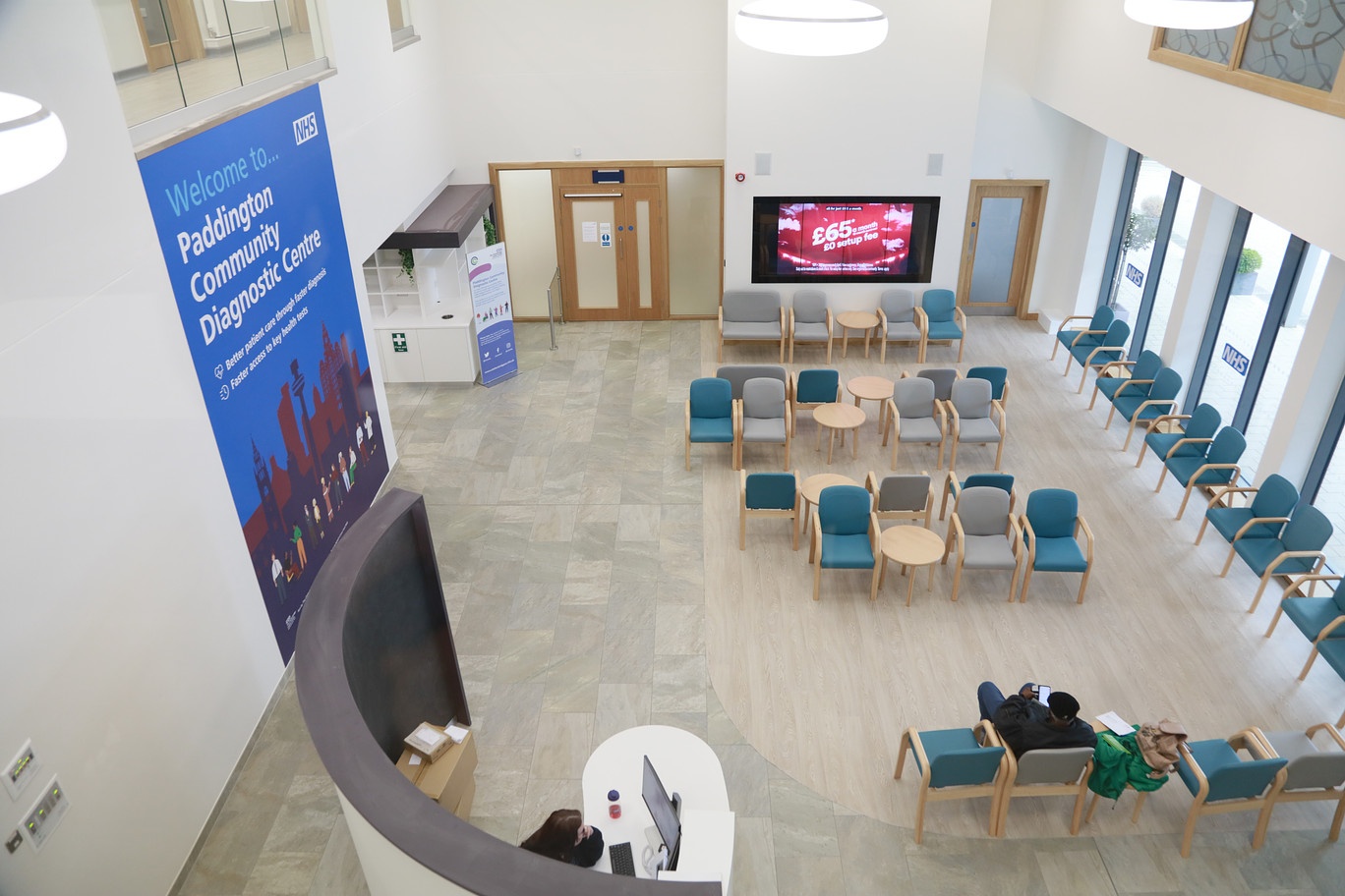 Aerial shot from above the main waiting area inside the diagnostic centre. It's a bright airy space with a large wall graphic that says Welcome to Paddington Community Diagnostic Centre