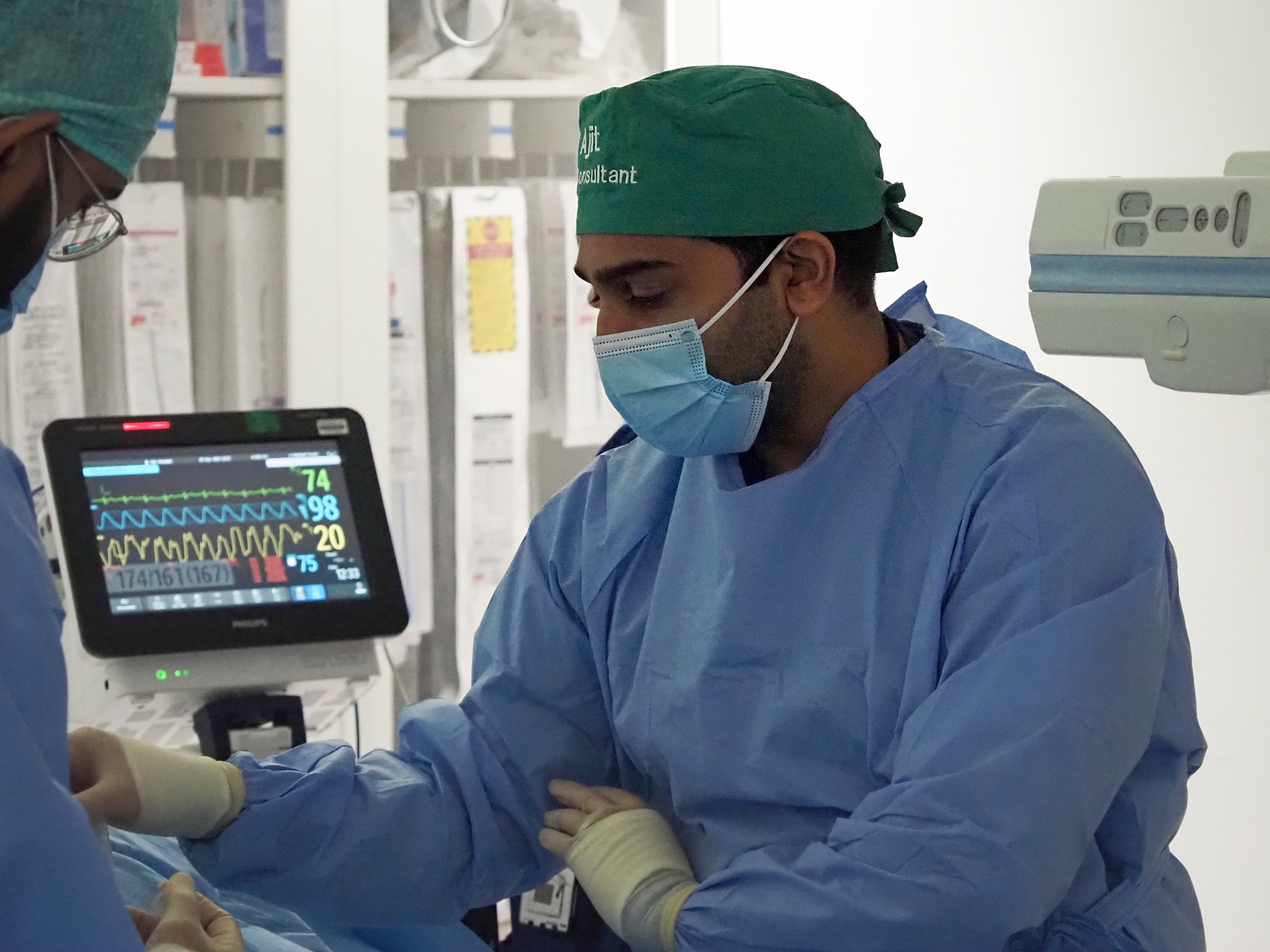 Dr Ajit Kishore performs a proceedure in a surgical theatre. He is wearing a green cotton reusable scurb cap. 