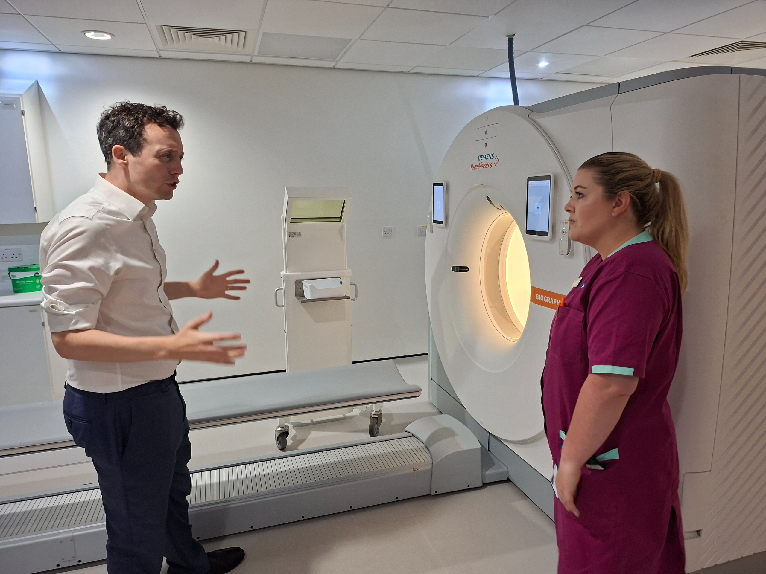 Two people looking at a PET-Ct scanner