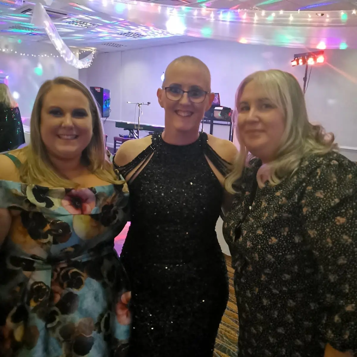 Kelly Barker (centre) with Halton unit manager Laura Selby (left) and a colleague (right). They are all dressed in glamorous evening dresses and are at Kelly's ball.