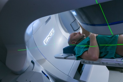 Patient on radiotherapy treatment bed. There are green laser beams to help the treatment team check the patient is in the correct position for treatment