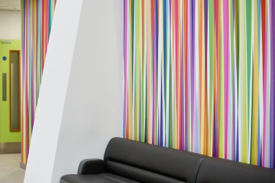 Hospital waiting area with brightly coloured artwork featuring stripes of different colours from floor to ceiling ©Rob Battersby