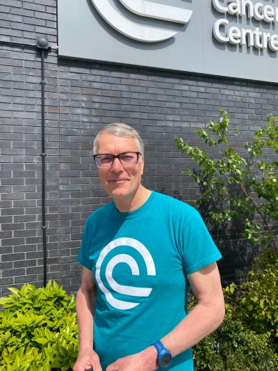 Male volunteer wearing a bright teal T-shirt standing outside the hospital in Liverpool