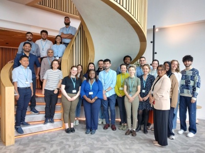 Group photo of new doctors gathered around a spiral staircase. They are smiling