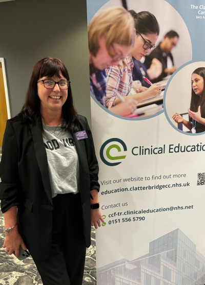 A female member of staff stands next to a banner promoting the Clinical Education Team at CCC
