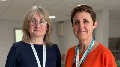 Catriona (left) has shoulder length dark blonde hair and glasses. Heulwen (right) has short dark hair. Both are smiling.