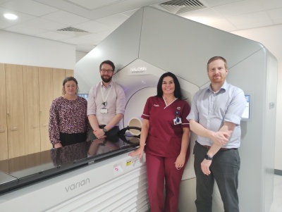 Hospital staff beside the new liac which is white and has a large O-shaped ring above a treatment bed