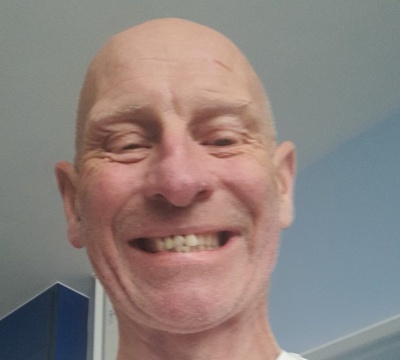 Selfie image of John who is smiling and wearing a T-shirt. He has a port in his arm for his cancer treatment