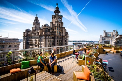 People relaxing in the Goodness Gracious rooftop garden with the famous Liver Building in the background
