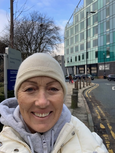 Anna-Louise is pictured across the road from the hospital. She is smiling and wearing a woolly hat